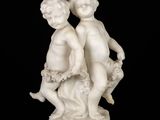 a white statue of two children sitting on top of a rock
