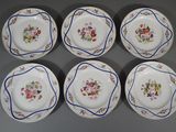 six assiettes ornées de motifs floraux sont disposées sur un fond gris