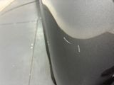 someone is peeling the paint off of a car ' s front bumper