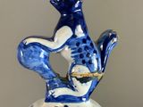 a blue and white vase with a cat sitting on top of it