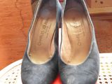 pair of black sued shoes sitting on top of a table next to a red box
