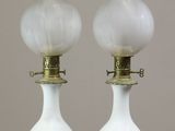 une paire de lampes en verre blanc avec des pieds en laiton, posées sur une surface blanche