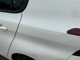 a white car that has a broken door handle on the side of the road