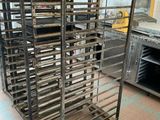 several trays of food sit on a metal rack in a kitchen