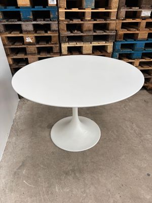 a white table in a warehouse with pallets in the background