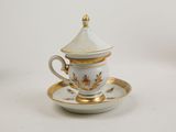 a white and gold cup and saucer on a saucer