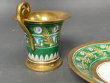 a green and gold cup and saucer on a table