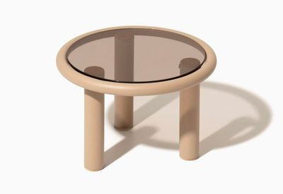 une petite table avec un plateau en verre, posée sur un meuble blanc