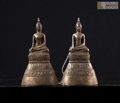 a pair of brass buddha statues sitting on top of a black surface
