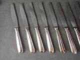 six silverplated knives are lined up on a table