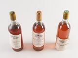 three bottles of wine sitting next to each other on a white surface