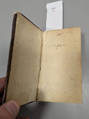 Quelqu'un tient dans sa main un vieux livre sur lequel figurent des inscriptions.