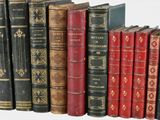 many old books lined up on a shelf in a row