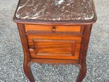 an old wooden table with a marble top on a gravel ground