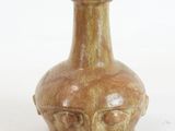 a brown vase with a face on it on a white surface