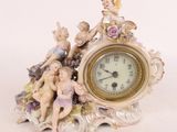 a clock with figurines on top of it on a table