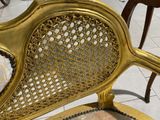 a gold chair with a cushion on it in the middle of a room