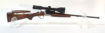 le fusil est posé sur un support transparent et est équipé d'une lunette de visée