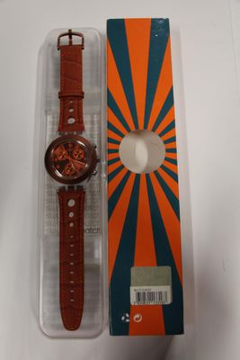 une montre orange et bleue posée sur une boîte blanche