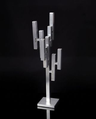 un gros plan d'une sculpture métallique posée sur un socle, sur fond noir
