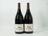 two bottles of red wine sitting next to each other on a table