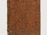 an old book with a brown cover sitting on a white surface
