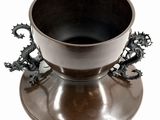 a metal cup with a dragon handle on a saucer