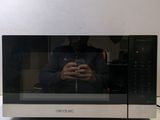 a man taking a picture of himself in front of a microwave