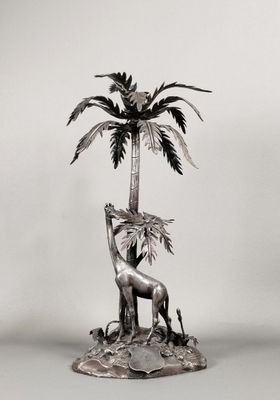 une statue en argent représentant une girafe et un palmier
