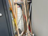 a pile of brooms and a shovel in front of a garage door