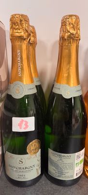 Trois bouteilles de champagne sont posées sur un comptoir, à côté d'une bouteille de vin
