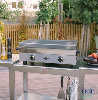a stainless steel grill on a table with a plate of food on it
