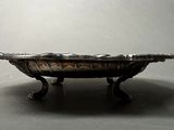 a small silver bowl on a stand on a table