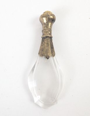 une image représentant une bouteille en verre munie d'une poignée métallique, posée sur une surface blanche