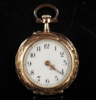 gros plan d'une montre de poche en or sur une surface noire
