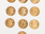 un gros plan sur plusieurs pièces d'or posées sur une surface blanche