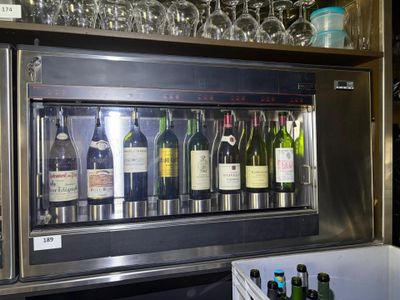 bottles of wine are lined up behind a wine cooler in a bar