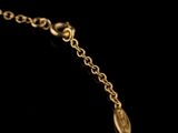 a close up of a gold chain with a leaf charm on it