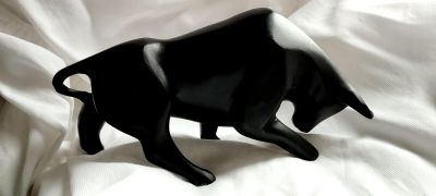 une figurine représentant un taureau noir, posée sur un drap blanc