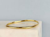 a close up of a gold bang bracelet on a marble block