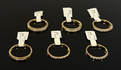 six gold rings with diamonds on them sitting on a black surface