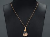 a gold plated necklace with a glass bottle on a mannequin