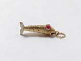 a close up of a gold fish charm on a white surface
