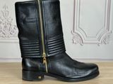 a pair of black leather boots with zippers on a wooden table