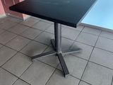 black square table with a metal base on a tiled floor