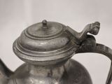 a silver tea pot with a handle on a table