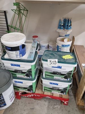 Plusieurs seaux de peinture sont empilés sur une étagère dans un garage