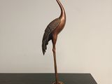statue d'une grue posée sur un socle, sur une table noire