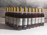 several bottles of wine are lined up in a row in front of a stone wall
