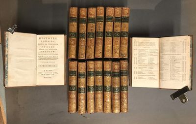un livre ouvert posé sur une table, à côté d'une pile de livres